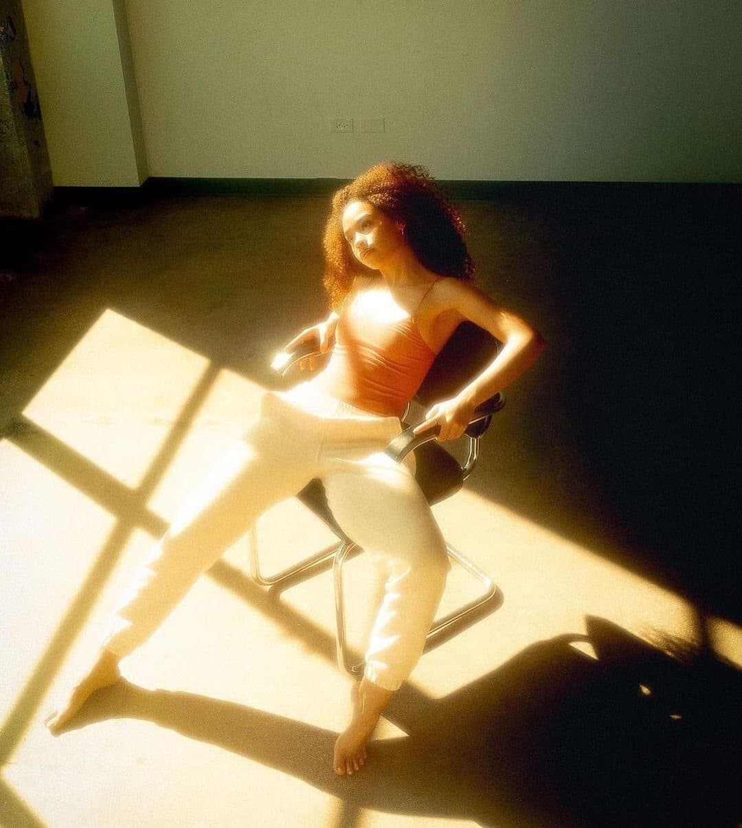 Dancer posing inside a window-shaped patch of sunlight on the studio floor